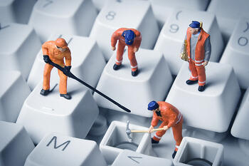 Miniature construction workers repairing a computer during downtime